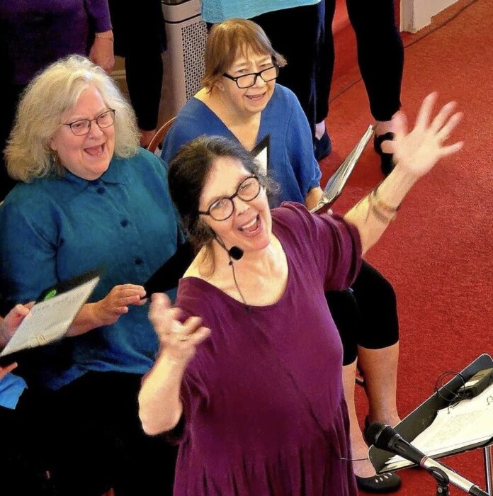 A woman raising her hands in song with two women behind her.