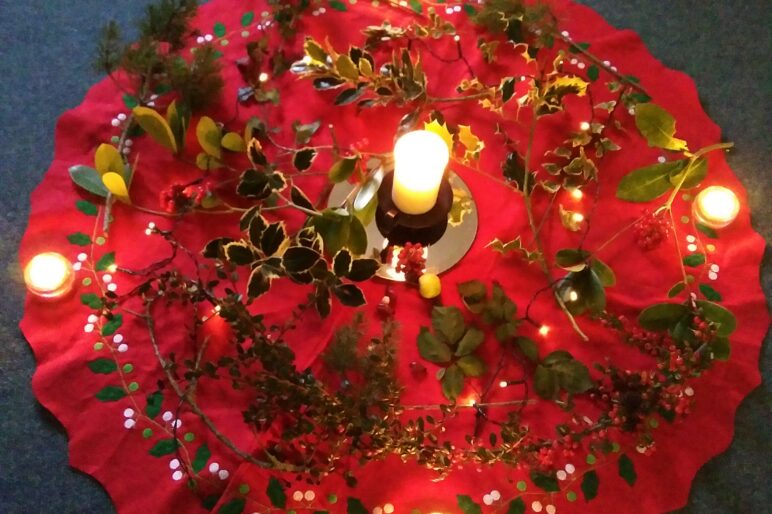 A floor mandala with candles and holly